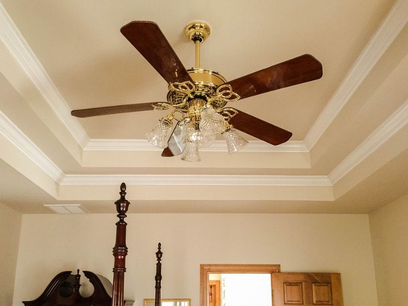a tray ceiling with a crown molding and a lighting fixture at the center