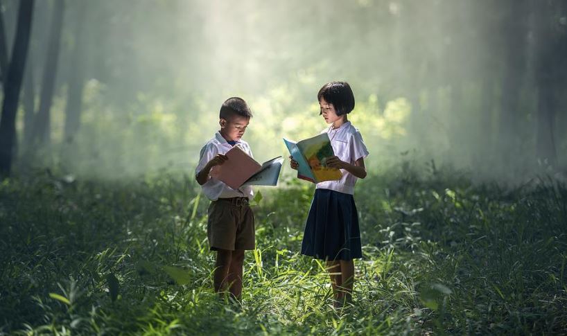 A boy and a Girl Reading a book in a forest like environment