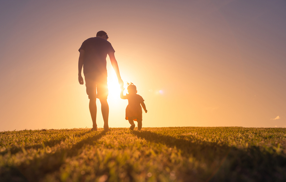 Father and daughter walking at sunset outdoors